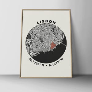 May include: A framed wall art print featuring a circular black and white map of Lisbon, Portugal. The city streets are depicted in black lines on a white background, with one specific area highlighted in red. The text LISBON and coordinates 38.7223 N 9.1393 W are printed in black.