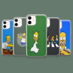 May include: Five clear smartphone cases featuring various illustrations of Homer Simpson. Designs include Homer emerging from a hedge, holding a beer mug with text, walking across a crosswalk, eating a snack, and reacting with an angry expression.