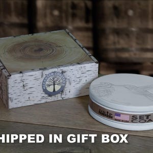 May include: A set of four white ceramic coasters with a hummingbird design. The coasters are packaged in a white gift box with a birch bark pattern and the text "McCarter Coasters" printed on the box.