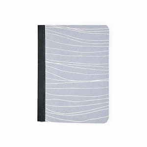 May include: A gray notebook with a black spine and a white wavy pattern on the cover.
