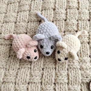 May include: Three small, plush, crocheted mouse figures in soft pastel colours: one light pink, one light grey, and one cream. Each mouse features a rounded body, two small ears, a thin tail, and two black bead eyes with a small black nose.