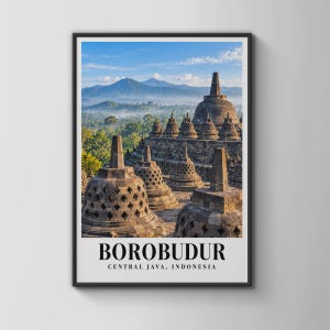 Peut inclure: Une impression d'art mural verticale encadrée représentant le temple de Borobudur à Java central, en Indonésie. L'image montre des stupas en pierre avec des découpes en forme de losange sur fond d'arbres verts, de montagnes et ciel bleu.