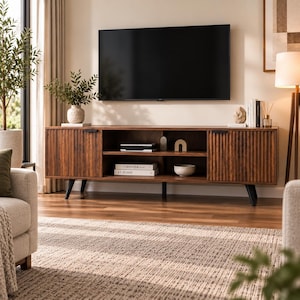 May include: A long, rectangular dark wood media console featuring two side cabinets with vertical fluted detailing, black metal handles, and an open central shelving unit with two levels. The unit is supported by four tapered black legs.