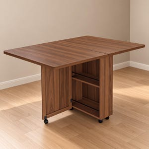 Pode incluir: Uma mesa dobr&aacute;vel cor de nogueira com tampo retangular e uma unidade de armazenamento central com duas prateleiras abertas. A mesa &eacute; apoiada por uma perna de painel articulada e uma base fixa, ambas equipadas com pequenas rodas pretas.