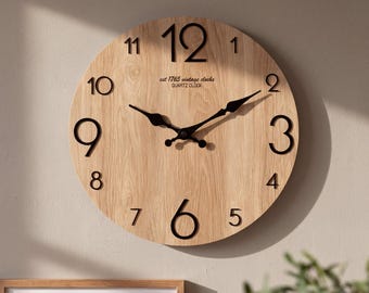 May include: A round wall clock with a light brown wood grain face and large black numerals. The clock features black metal hands and the text "est 1765 vintage clocks QUARTZ CLOCK" printed in black below the twelve o'clock position.