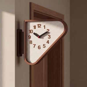 Puede incluir: Un reloj de pared con marco triangular en acabado marrón oscuro. La esfera presenta un fondo blanco con patrón de cuadrícula y números de color marrón oscuro del 1 al 12. Tiene dos manecillas oscuras y una pequeña tapa central roja.