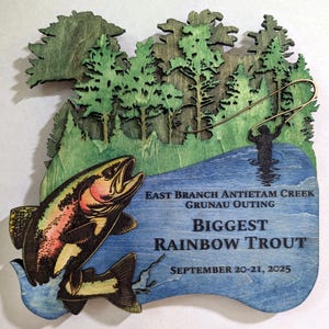 Könnte beinhalten: Holztafel mit einer Regenbogenforelle, die aus blauem Wasser springt, mit einer Fischer-Silhouette. Der Text "East Branch Antietam Creek Grunau Outing BIGGEST RAINBOW TROUT September 20-21, 2025" ist enthalten. Oben befindet sich ein Waldmotiv.