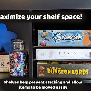 May include: A black shelf unit with three shelves, each holding board games. The top shelf has a blue game piece, a glass jar filled with dice, and a board game called "Era: Medieval Age". The second shelf has a board game called "Seasons" and the third shelf has a board game called "Brass: Birmingham" and a board game called "Dungeon Lords". The text "Maximize your shelf space!" is at the top of the image and the text "Shelves help prevent stacking and allow items to be moved easily" is at the bottom of the image.