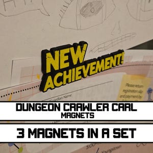 Może przedstawiać: Trójwymiarowy magnes z napisem NEW ACHIEVEMENT! pogrubionymi żółtymi literami z grubym czarnym obrysem. Magnes jest przymocowany do powierzchni, na której znajdują się różne papiery z odręcznymi rysunkami i drukowanym tekstem.