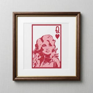 May include: A framed cross-stitch embroidery featuring a stylized portrait of a woman with voluminous hair, designed to resemble a playing card. The artwork includes the letter Q and a heart symbol in red thread against a white fabric background.