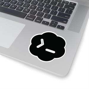 May include: A black cloud-shaped sticker with a white border featuring a white command line prompt symbol consisting of a chevron and an underscore. The sticker is applied to the surface of a silver laptop near the keyboard and trackpad area.