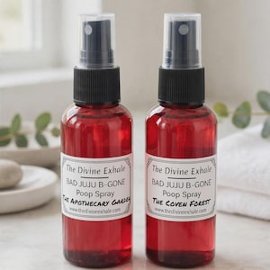 May include: Two clear red plastic spray bottles with black pump nozzles. Each bottle features a white rectangular label with black text reading The Divine Exhale, BAD JUJU B-GONE, Poop Spray, and either THE APOTHECARY GARDEN or THE COVEN FOREST.