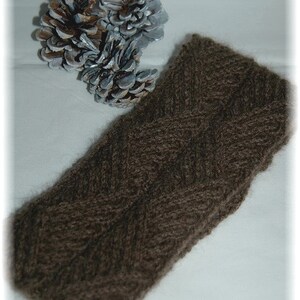May include: A brown knitted headband with a chevron pattern. The headband is made of a soft, fuzzy yarn.