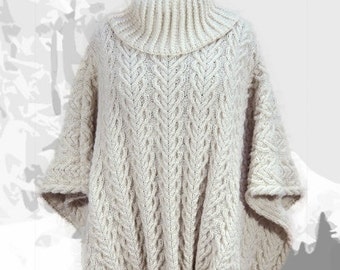 May include: A cream-colored knitted poncho with a high turtleneck and a cable knit pattern.