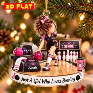 May include: A flat acrylic Christmas ornament featuring a bowling scene with a character throwing a pink ball. The design includes a bowling lane, pins, a bag labeled Sophia, and the text 2D FLAT and Just A Girl Who Loves Bowling.