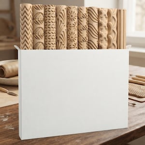 May include: A collection of ten cylindrical wooden rolling pins with various carved patterns, including zigzags, leaves, flowers, and geometric shapes, arranged upright inside a plain white rectangular storage box for display and organization.