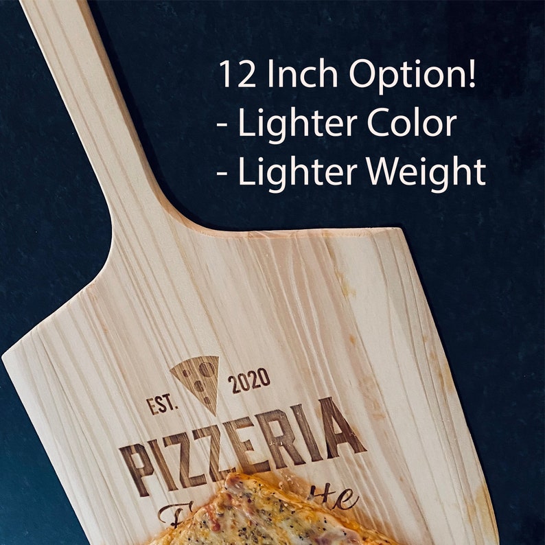 May include: A wooden pizza peel with a handle, featuring the text "PIZZERIA" and "EST. 2020". The peel is light-colored and has the text "12 Inch Option! - Lighter Color - Lighter Weight". A pizza is partially visible on the peel.