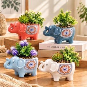 May include: Four ceramic elephant-shaped planters in coral, blue, light blue, and white. Each features a decorative orange and blue floral pattern on the side, closed eyes, and contains a small artificial green or purple plant.