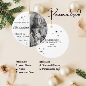 Può includere: Due ornamenti rotondi in ceramica bianca con cordini dorati. Uno presenta una foto in bianco e nero di una donna e un bambino con il testo Your light shines on Grandma FOREVER IN OUR HEARTS 1940-2026. L'altro mostra FOREVER LOVED-NEVER FORGOTTEN.
