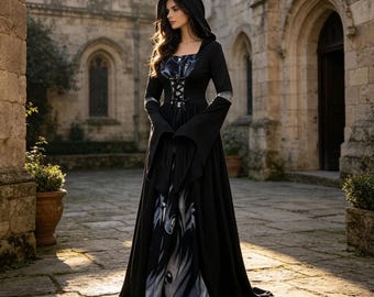 Può includere: Un abito nero lungo fino ai piedi con cappuccio, maniche lunghe svasate, corpetto in stile corsetto con allacciatura e gonna fluida con stampa grafica astratta grigia e bianca. Il capo presenta una vita aderente e un cappuccio sulle spalle.