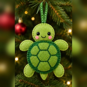 May include: A felt turtle ornament in shades of light and dark green with a stitched shell pattern, black bead eyes, and pink circular cheeks. The turtle has a small green ribbon loop at the top for hanging on a Christmas tree branch.
