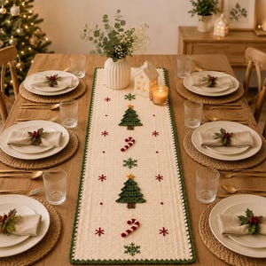 May include: A rectangular cream-coloured crochet table runner featuring a dark green border and embroidered Christmas motifs including green pine trees, red and white candy canes, and small red and green snowflakes arranged in a vertical pattern.