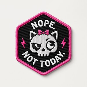 May include: A hexagonal embroidered patch with a black background and a bright pink border. It features a white cat skull with a pink bow, surrounded by the white text NOPE. NOT TODAY. and two small pink lightning bolts on the sides.