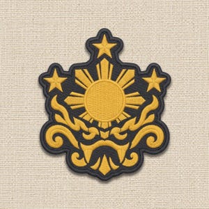 May include: An embroidered patch featuring a central golden sun with eight rays, positioned above a stylized golden scrollwork design. Three golden five-pointed stars are arranged around the sun, all set against a dark navy blue background.