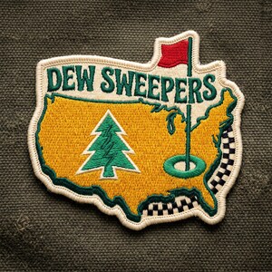 May include: An embroidered patch shaped like the United States map in yellow with a green pine tree, a red golf flag, and a green golf hole. The text DEW SWEEPERS is stitched in green across the top. The border is cream with a black and white checkered pattern.