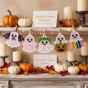 May include: A string of five embroidered ghost ornaments hanging from a wire with wooden clips. The ghosts feature various designs including purple bat wings, a pink heart, a green leaf crown, an orange pumpkin, and a rainbow fringe base.