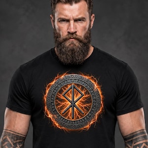 Pode incluir: Uma t-shirt preta de manga curta com um gr&aacute;fico circular no peito. O design apresenta uma runa Othala central rodeada por um anel de inscri&ccedil;&otilde;es r&uacute;nicas, tudo rodeado por um efeito de rel&acirc;mpago laranja brilhante.