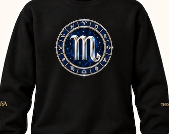 May include: A black long-sleeve sweatshirt featuring a central circular graphic of the Scorpio zodiac symbol in silver. The symbol is surrounded by a blue ring containing all twelve zodiac signs against a starry, deep blue nebula background.
