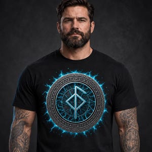 Może przedstawiać: Czarny t-shirt z kr&oacute;tkim rękawem z centralną grafiką metalicznego symbolu runicznego zamkniętego w okrągłej ramie. Wz&oacute;r otoczony jest świecącymi niebieskimi błyskawicami energii elektrycznej oraz skomplikowanym tekstem runicznym na obrzeżach.