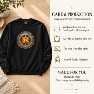 May include: A black crewneck sweatshirt featuring a circular graphic with a glowing orange rune symbol surrounded by a metallic border. The text CARE & PRODUCTION, MADE FOR YOU, and care instructions are printed on the right side of the image.