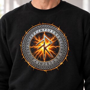 May include: A black crewneck sweatshirt featuring a central circular graphic. The design includes a metallic silver rune symbol surrounded by a ring of glowing orange lightning and a border of intricate silver Celtic knotwork patterns.