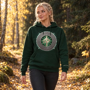May include: A dark green hooded sweatshirt featuring a central circular graphic with a metallic-toned runic symbol, surrounded by a ring of Norse-style knotwork and a glowing green light effect, with a front kangaroo pocket and long sleeves.