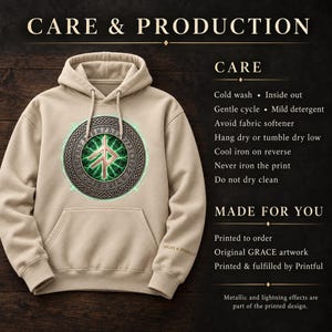 May include: A beige hooded sweatshirt featuring a central graphic of a glowing green rune inside a circular metallic border. Text on the right includes CARE & PRODUCTION, CARE instructions, and MADE FOR YOU details regarding the print.