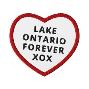Peut inclure: Un écusson brodé en forme de cœur avec un centre blanc et une bordure rouge. Le texte LAKE ONTARIO FOREVER XOX est cousu en fil noir au centre de l'écusson. Le motif présente une police d'écriture grasse et une finition à bord cousu.