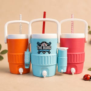 May include: Three colorful beverage coolers with white handles and spouts. The coolers are orange, light blue with a baseball logo, and pink. Each cooler has a matching straw. A ladybug and greenery are in the background.