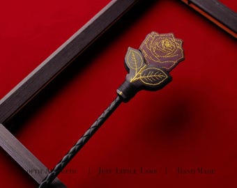 May include: A black braided handle crop featuring a dark maroon rose topper with intricate gold thread embroidery detailing the petals and leaves. The text "SOFTIE AESTHETIC | JUST LITTLE LAMB | HAND MADE" is visible in the lower portion of the image.