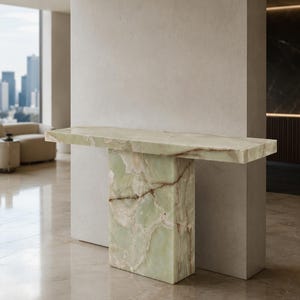 May include: A console table crafted from light green onyx stone with natural white and brown veining. The piece features a rectangular top supported by a single thick, vertical slab base, showcasing a polished, smooth surface throughout.