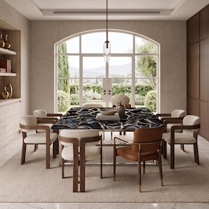 May include: A rectangular dining table with a polished black and blue agate stone top, surrounded by six armchairs featuring dark wood frames and cream-colored upholstery, with one chair upholstered in tan leather, set in a dining room.