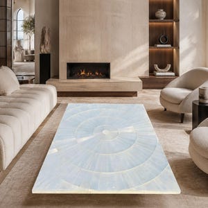 May include: A rectangular coffee table featuring a light blue, translucent stone surface with a radial, circular pattern composed of segmented pieces. The table has a smooth, polished finish and is positioned centrally in a living room space.