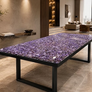 Puede incluir: Una mesa de comedor rectangular con una superficie pulida compuesta por numerosos fragmentos de piedras preciosas de amatista de color púrpura intenso. El tablero está sostenido por una estructura de metal negro con cuatro patas.