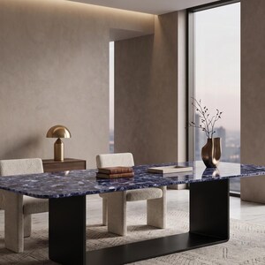 Puede incluir: Una mesa de comedor rectangular con un tablero de piedra preciosa azul profundo pulido con textura cristalina natural, apoyada sobre una base negra sólida en forma de U. La mesa incluye dos sillas tapizadas de color crema.