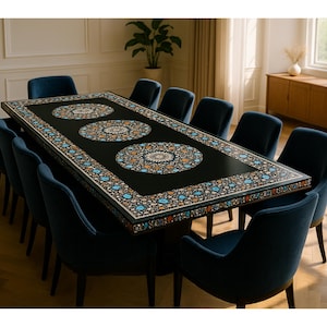 Puede incluir: Una mesa de comedor rectangular con superficie negra que presenta tres grandes incrustaciones circulares estilo mandala y un borde floral decorativo en tonos azul, naranja y blanco, rodeada por doce sillas de comedor tapizadas en azul oscuro.