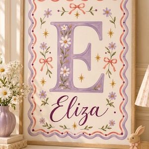Pode incluir: Uma impressão artística emoldurada com uma letra E grande e roxa decorada com margaridas brancas e vinhas verdes. Abaixo da letra, o nome Eliza está escrito em letra cursiva roxa. A borda é uma linha roxa ondulada com fitas cor-de-rosa.