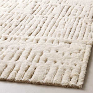 May include: An off-white area rug featuring a high-pile, textured surface with a repeating geometric pattern of raised, parallel rectangular blocks. The design creates a tactile, three-dimensional effect across the entire surface of the rug.