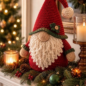 Può includere: Una statuetta di gnomo all'uncinetto con un alto cappello a punta rosso con un pompon bianco, una lunga barba bianca testurizzata e un naso rotondo beige. Lo gnomo ha un corpo rosso con polsini verdi e un bordo verde sul cappello con un bottone.