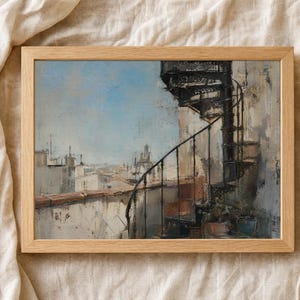 May include: A framed art print featuring an oil painting of a black metal spiral staircase on a rooftop terrace overlooking a city skyline under a pale blue sky. The scene includes weathered stone walls, terracotta roof edges, and soft light.